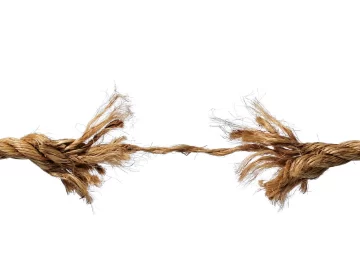 Frayed rope about to break isolated over a white background