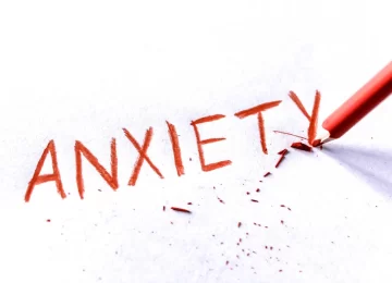 Anxiety concept. Word anxiety written on white paper with red pencil. Pencil broken.