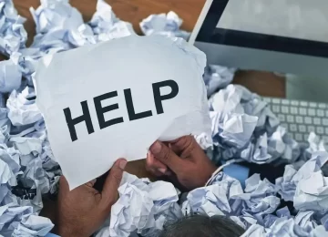 Shot of an unidentifiable businessman asking for help while drowning under a pile of paperwork.