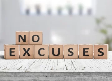 No excuses sign in a bright room on a wooden table with worn planks