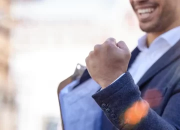 Shot of a businessman cheering in excitement while holding a clipboard.