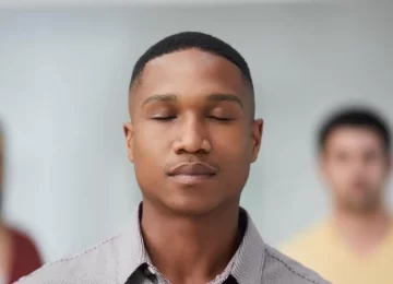 Shot of a group of young businesspeople standing in a modern office with their eyes closed.