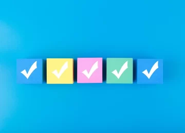 Five checkmarks on multicolored cubes in a row on blue background with copy space. Concept of questionary, checklist, to do list, planning, business or verification. Modern minimal composition