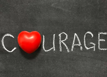 courage word handwritten on  chalkboard with heart symbol instead of O